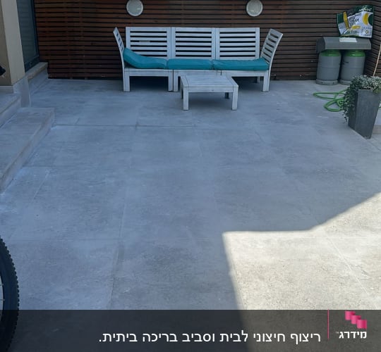 מרפסת עם ריצוף חדש, צינור ירוק ופח אשפה